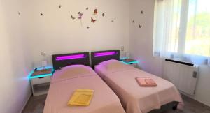 a room with two beds with purple lights on them at Maison neuve Jacuzzi et Piscine Haut de Gamme in Vallon-Pont-dʼArc