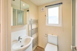 a bathroom with a sink and a toilet and a window at Nightingale Lodge with Hot Tub in Barmby on the Moor +30 photos