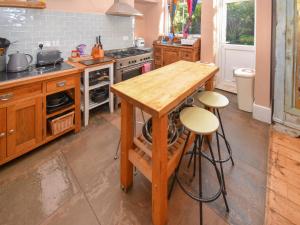 a kitchen with a wooden table and two stools at Sunnycote in Arnside