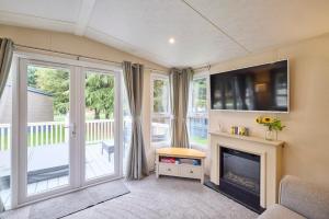 a living room with a fireplace and a tv at Nightingale Lodge with Hot Tub in Barmby on the Moor