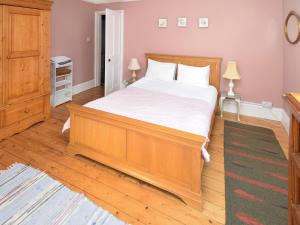 a bedroom with a large wooden bed with white sheets at Sunnycote in Arnside