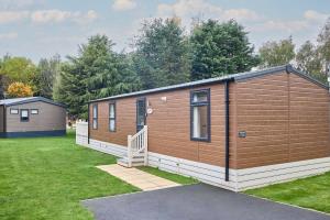a large wooden cabin with a grass yard at Nightingale Lodge with Hot Tub in Barmby on the Moor