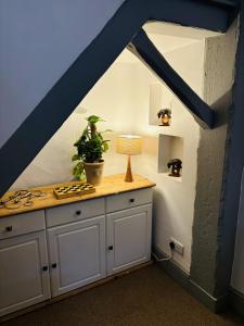 a kitchen with white cabinets and a table with a lamp at Above the Bear in Wiveliscombe