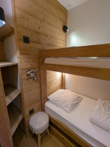 ティーニュにあるAppartement au lac ski aux piedsの小さな客室で、二段ベッド2台、スツールが備わります。