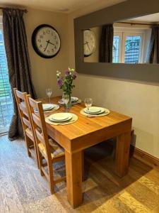 une table de salle à manger avec des chaises et des horloges au mur dans l'établissement Surrounded by fields just 3 miles from Stratford - upon Avon - Alveston Pastures Retreat, à Stratford-upon-Avon