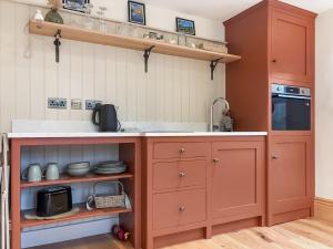 a kitchen with red cabinets and a sink at The Coal House in Skipton