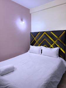 a bedroom with a white bed with a black headboard at CHS Vacation Stays Limited in Kampala