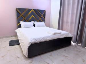 a bedroom with a large bed with white sheets and pillows at CHS Vacation Stays Limited in Kampala