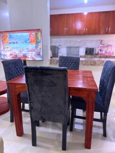 a wooden table and chairs with a kitchen in the background at CHS Vacation Stays Limited in Kampala +8 photos