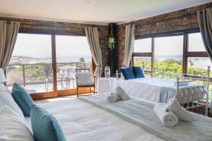 two beds in a room with large windows at White Shark Guest House in Gansbaai