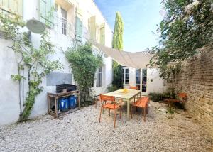 eine Terrasse mit einem Tisch, Stühlen und einem Grill in der Unterkunft HORIZON grande maison de charme à La Couarde in La Couarde-sur-Mer