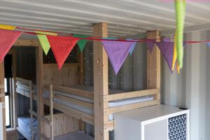 a room with bunk beds with colorful flags at Container 11, Camp Tapnell in Yarmouth +24 photos