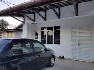 a car parked in front of a white house at Ummi Guesthouse in Dungun