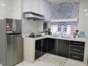 a white kitchen with a sink and a refrigerator at Ummi Guesthouse in Dungun