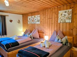 two beds in a room with wooden walls at Lampererhof in Sankt Johann in Tirol