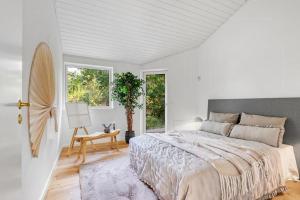 a white bedroom with a large bed and a chair at Architect-Designed Holiday Home Close To The Water in Marielyst