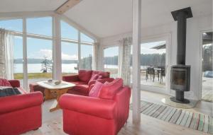 a living room with red chairs and a fireplace at 3 Bedroom Beautiful Home In Årjäng in Årjäng