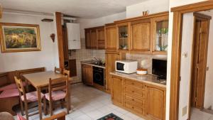 a kitchen with wooden cabinets and a table with a microwave at Appartamento vicino a Bormio in Valdisotto