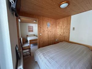 a bedroom with a bed and a chair in a room at Auberge le bois du cornet in La Forclaz