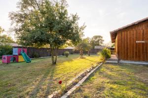 un jardin avec une aire de jeux et un arbre dans l'établissement Lou Cabanot 640 portes du Bassin, à Le Barp