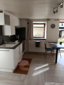 cocina con armarios blancos, mesa y ventana en Escapade cosy à Voglans avec terrasse au calme, en Voglans