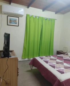 1 dormitorio con cortina verde y cama en Departamentos Susana & Aldo, en Valle Hermoso 2 fotos más