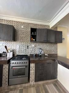 una cocina con estufa y gabinetes marrones en Tamara Apartments, en Mombasa