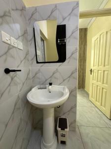 Un baño con un lavabo blanco y un espejo. en Tamara Apartments, en Mombasa