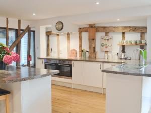 a kitchen with white cabinets and a clock on the wall at Burfields Barn in Rickinghall