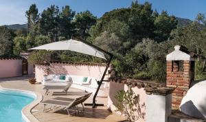 a patio with an umbrella and chairs next to a pool at Villa Fiori 4 in Is Molas  +15 photos