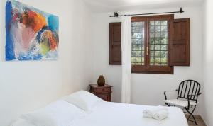 a bedroom with a bed and a chair and a painting at Villa Fiori 4 in Is Molas 