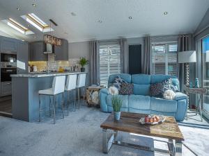 a living room with a blue couch and a kitchen at 36 At The Sanctuary - Uk50278 in Carnguwch