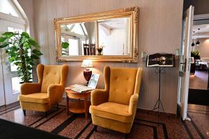 a living room with two chairs and a mirror at Hotel Piast in Opole
