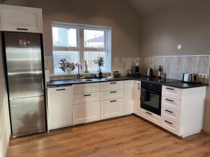 a kitchen with white cabinets and a stainless steel refrigerator at Guesthouse Hvammur by the Harbour in Höfn +46 photos