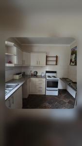 a kitchen with white cabinets and a stove top oven at Bunkers Accomodation in Underberg