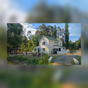 a white house with a green roof on a field at Bunkers Accomodation in Underberg
