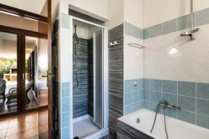 een badkamer met een bad en een douche met blauwe tegels bij Villa Palme in Monte Nai
