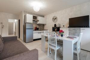 eine Küche und ein Wohnzimmer mit einem weißen Tisch und Stühlen in der Unterkunft Kamélia - 10min des pistes in Xonrupt-Longemer + 4 Fotos
