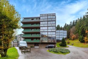 ein Gebäude mit einem auf einem Parkplatz geparkten Auto in der Unterkunft Kamélia - 10min des pistes in Xonrupt-Longemer
