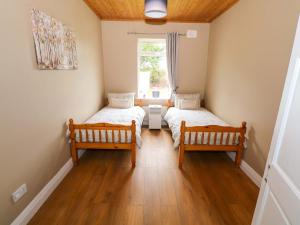 two beds in a room with wooden floors and a window at Carrowreagh in Aclare