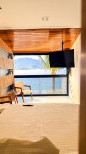 a bedroom with a large window with a view of the ocean at Residencial Solariun Ilhabela in Ilhabela