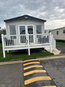 ein weißes Haus mit Veranda am Straßenrand in der Unterkunft Haven Blackpool Fleetwood holiday park in Fleetwood