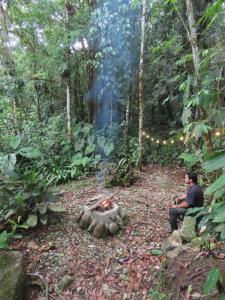two men sitting around a fire in a forest at Manacus 