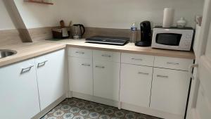 a kitchen with white cabinets and a microwave on a counter at T2 proche du CH d'Arras in Sainte-Catherine