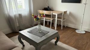 a vase of flowers on a table in a living room at T2 proche du CH d'Arras in Sainte-Catherine