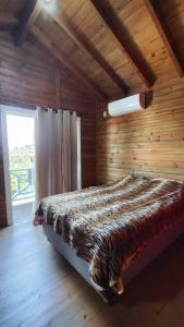 a bed in a wooden room with a window at Chalé do Alemão in Imbituba