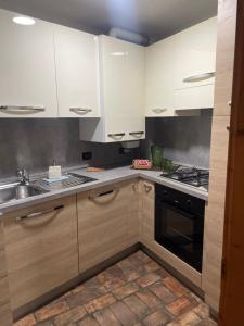 Una cocina con gabinetes blancos, un fregadero y una estufa. en Ca' Dei Sassi, en Sequsino 13 fotos más