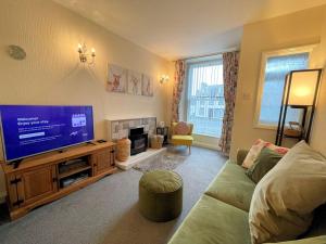 a living room with a couch and a flat screen tv at Pass the Keys Cosy Romantic Getaway with Hot Tub in Whithorn