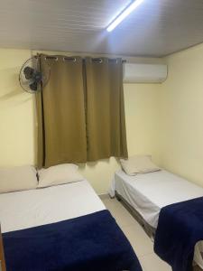 a room with two beds and a window with a fan at Pousada Centro Oeste in Trindade