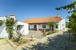 une maison blanche avec une cour fleurie dans l'établissement Montes de Praias GuestHouse, à Aljezur